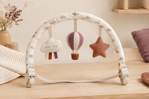 Arche d’éveil en coton Aomig fixée sur une poussette dans un décor doux et lumineux.