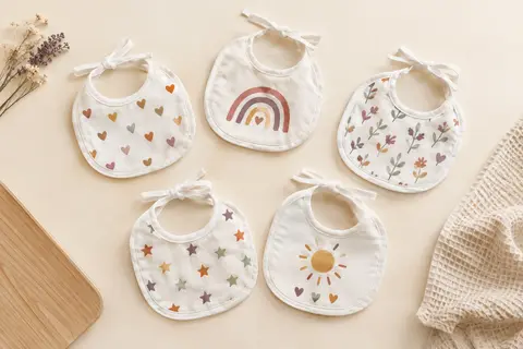 Lot de cinq bavoirs naissance blancs en éponge rase avec liens à nouer et impressions multicolores