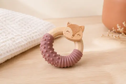 Anneau de dentition en silicone texturé et bois présenté sur un fond crème avec du bois clair.
