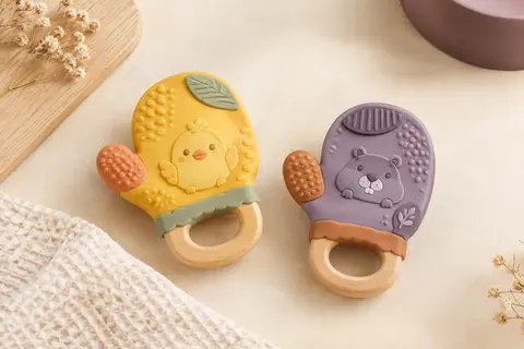 Deux jouets de dentition multicolores en forme de mitaine, aux motifs de poussin et de marmotte.
