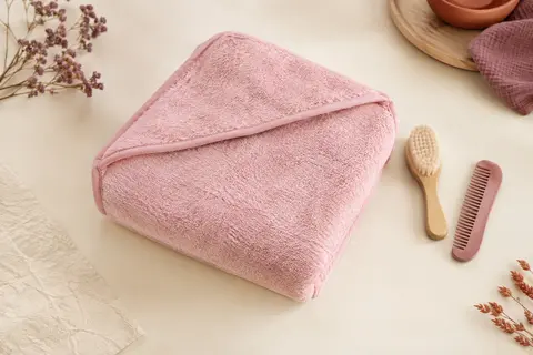 Cape de bain bébé rose en coton éponge avec capuche, accompagnée d’une brosse et d’un peigne assortis.