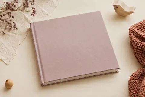 Journal de naissance à couverture rigide posé sur un fond crème près de papier texturé et de bois clair