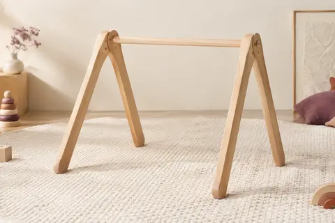 Arche d’éveil en bois de hêtre installée au-dessus d’un tapis crème dans un décor lumineux