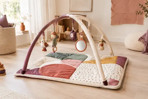 Tapis d’éveil réversible avec arches réglables et accessoires, posé dans un décor clair et chaleureux.