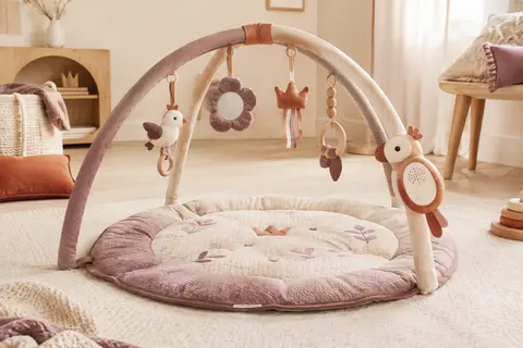 Tapis d’éveil Tiny Love avec arches, jouets suspendus, miroir et module musical sur un fond crème