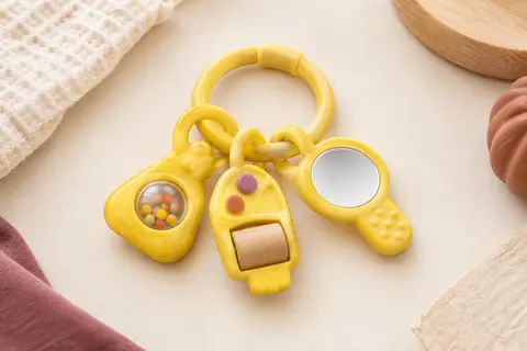 Hochet bébé jaune en forme de trousseau, avec boutons, clés, rouleau, billes et miroir.